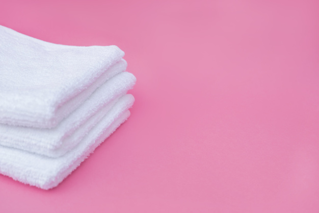 pilha-de-toalhas-brancas-em-fundo-rosa_23-2147927200